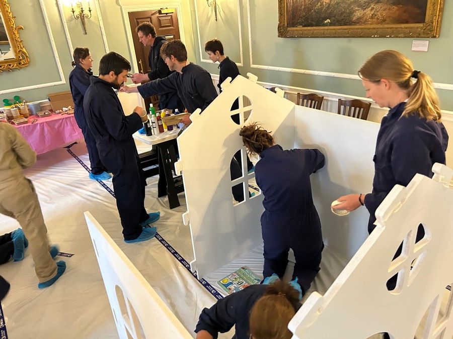 CSR team building: a team painting a wooden playhouse that goes to a children's centre