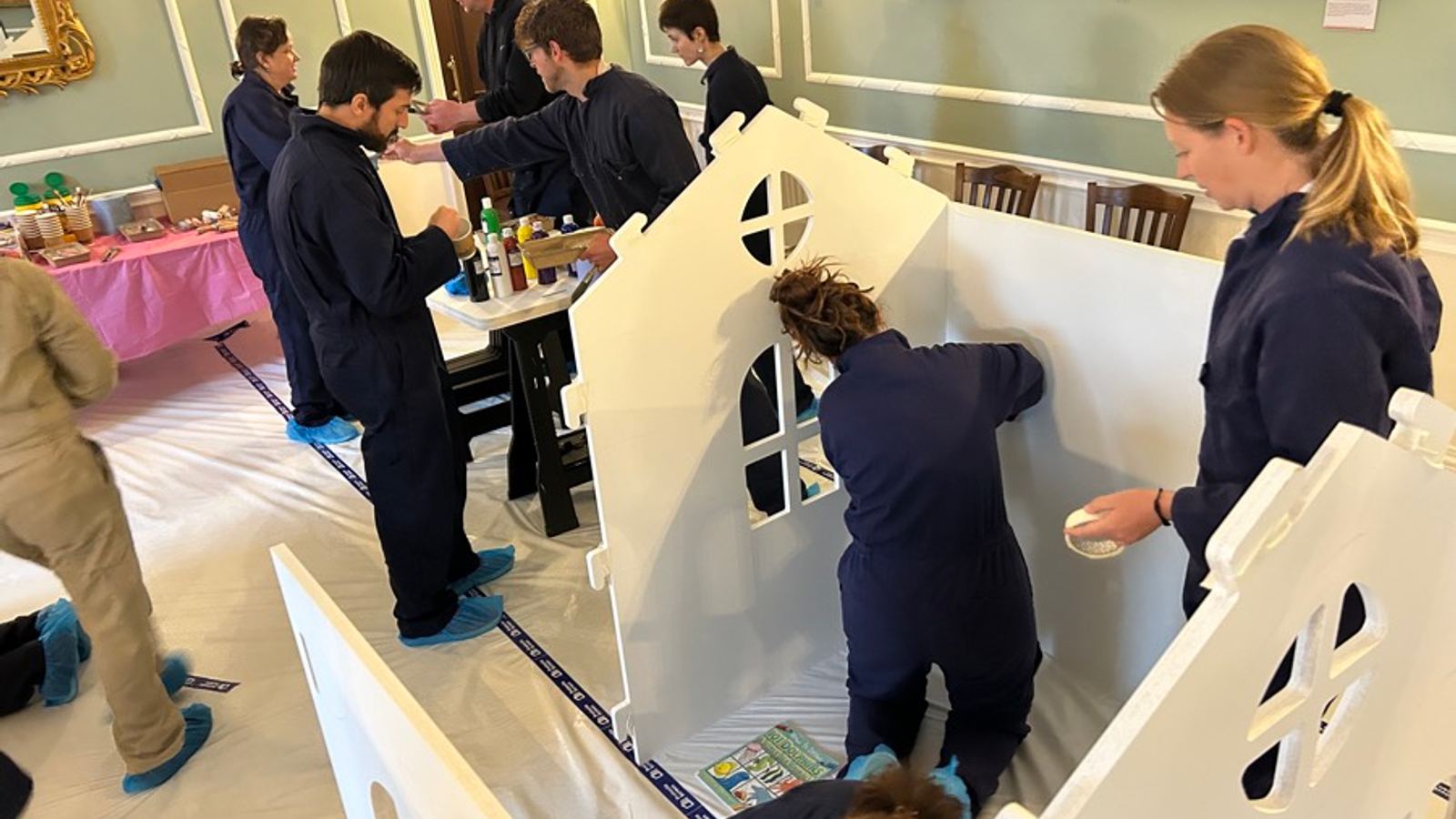 CSR team building: a team painting a wooden playhouse that goes to a children's centre