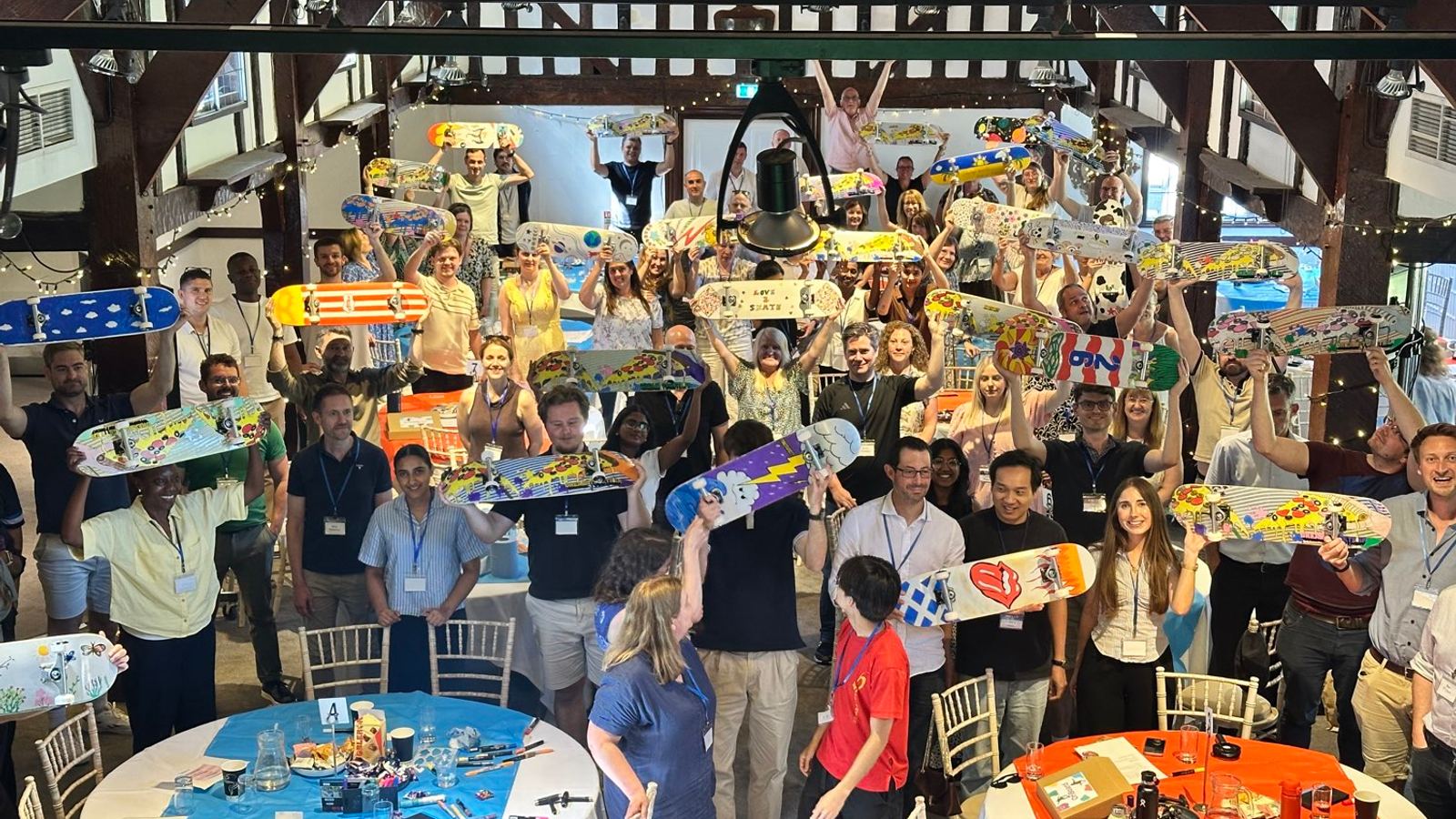 Christmas team building: a hall of people holding up the skateboards they built for a charity