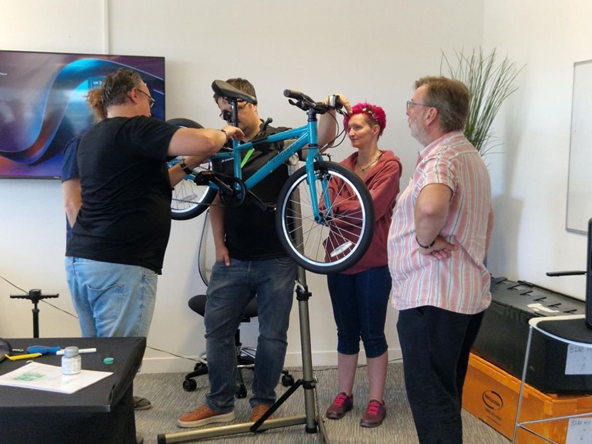 A team building and safety checking a bike on a workshop stand
