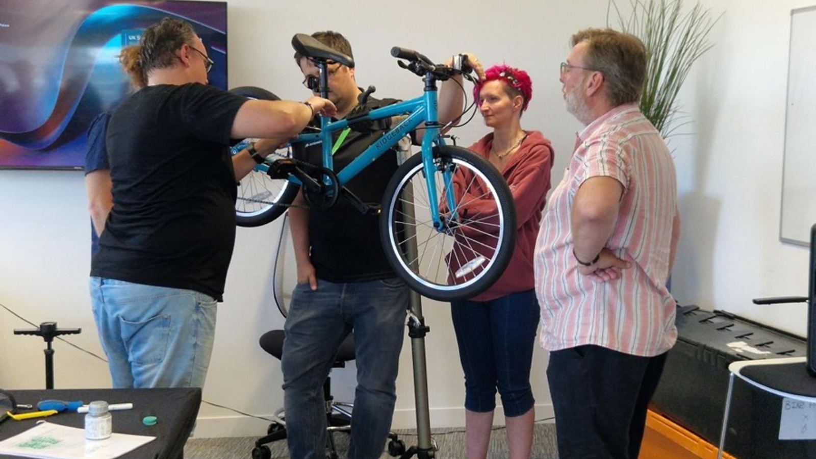 A charity bike build: colleagues fitting a wheel to a bike frame
