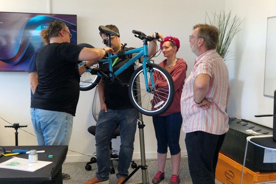 A team building and safety checking a bike on a workshop stand