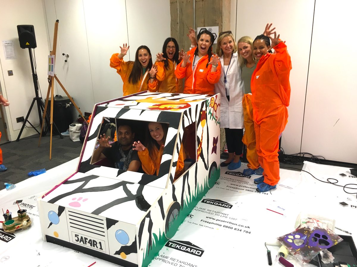 A team with the painted furniture they built for a charity