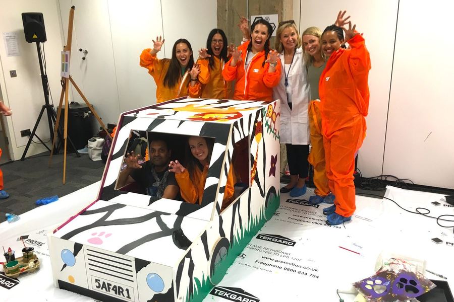 A team with the painted furniture they built for a charity