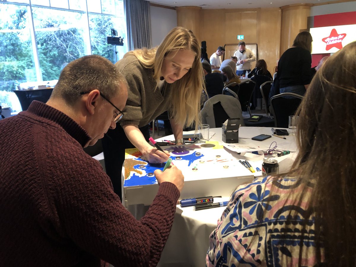 Team building for large groups: a hall of teams working through a charity building challenge