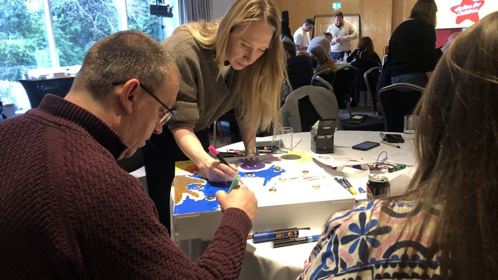 Team building for large groups: a hall of teams working through a charity building challenge