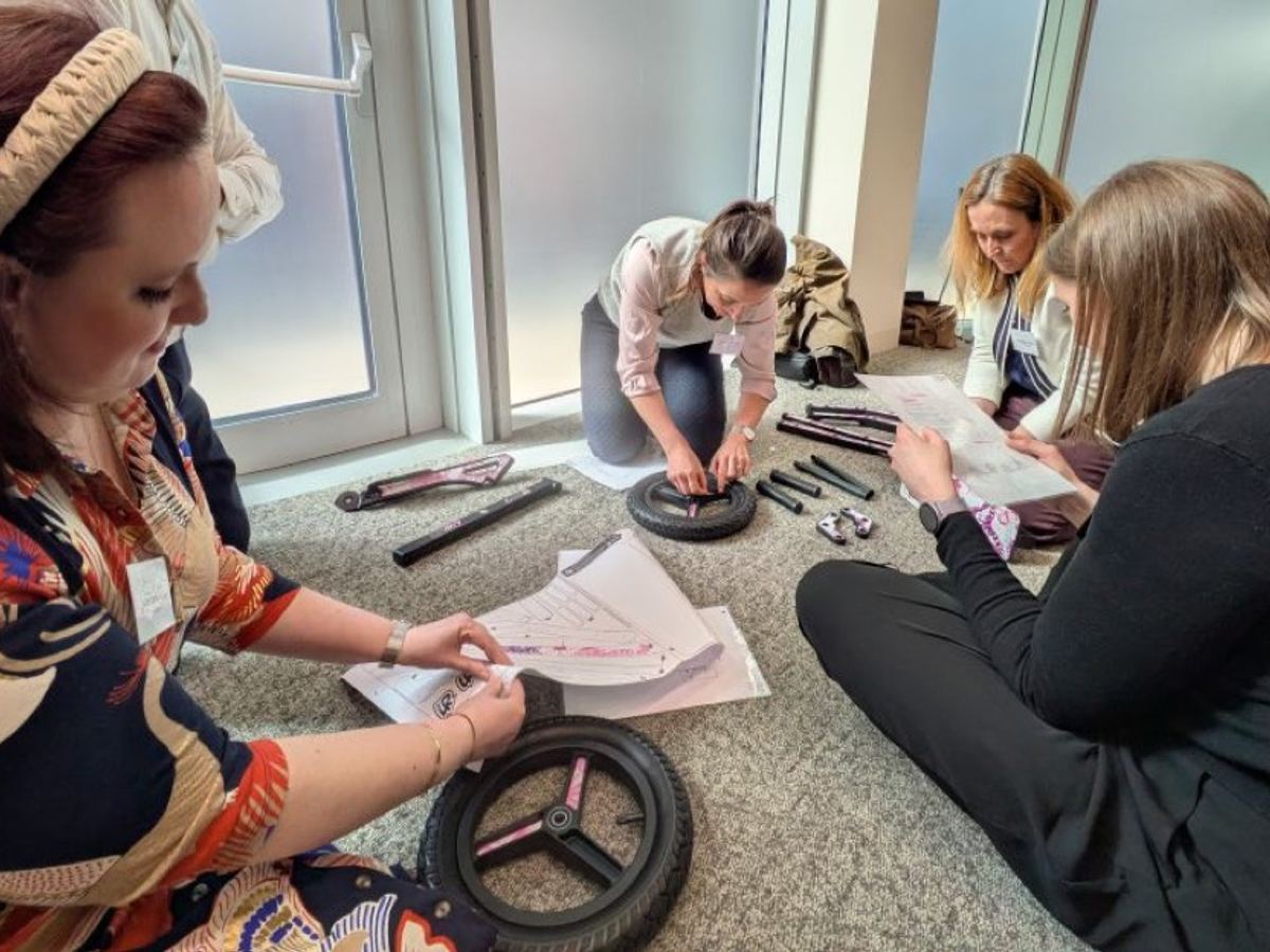 A team on the floor assembling scooter wheels from instructions