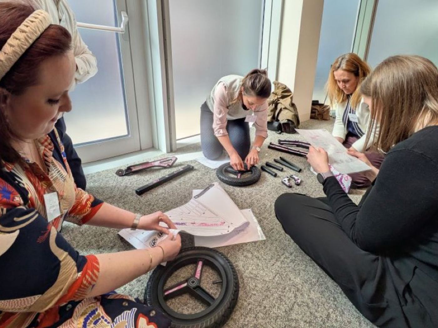 A team on the floor assembling scooter wheels from instructions