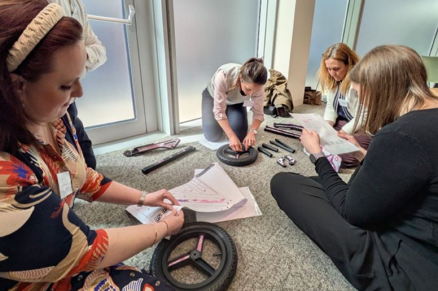 A team on the floor assembling scooter wheels from instructions