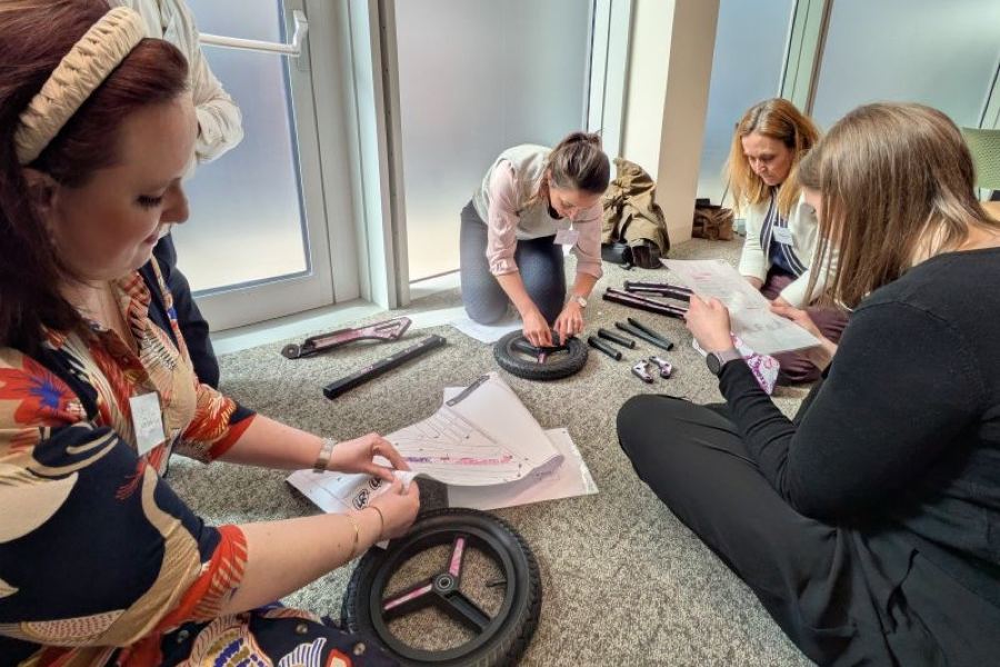 A team on the floor assembling scooter wheels from instructions