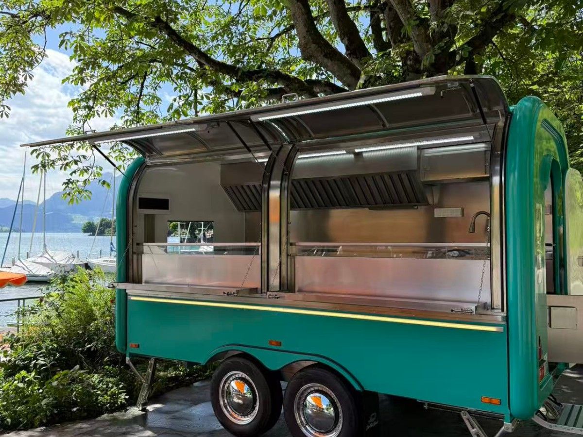 Green Chris Machinery food trailer parked by lake operating for outdoor catering