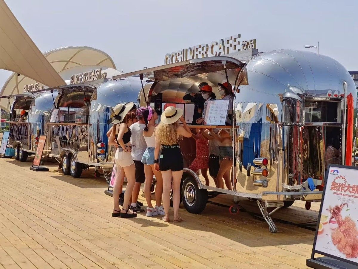Chris Machinery Airstream mobile bar trailer serving customers at sunny outdoor beach festival