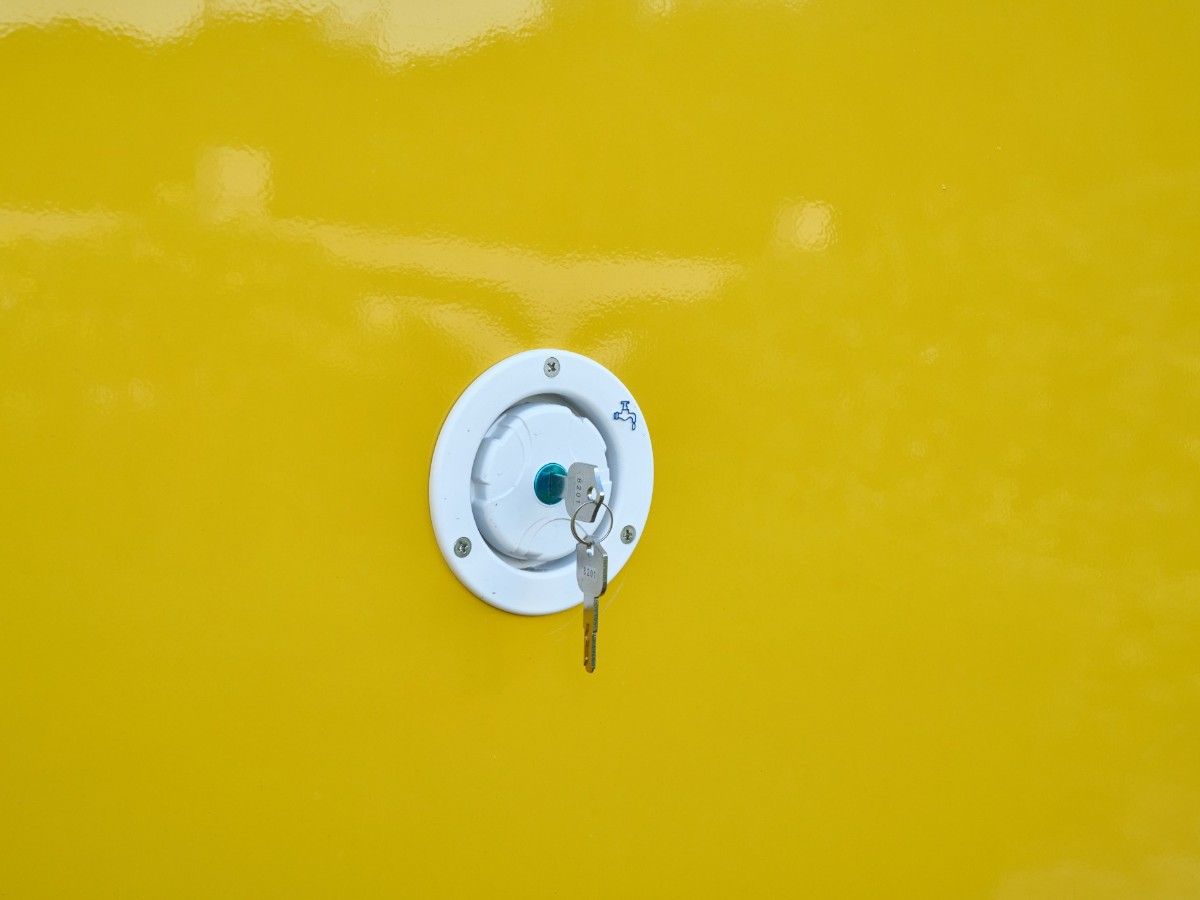 Water tank inlet cap with lock key mounted on a Chris Machinery yellow food trailer