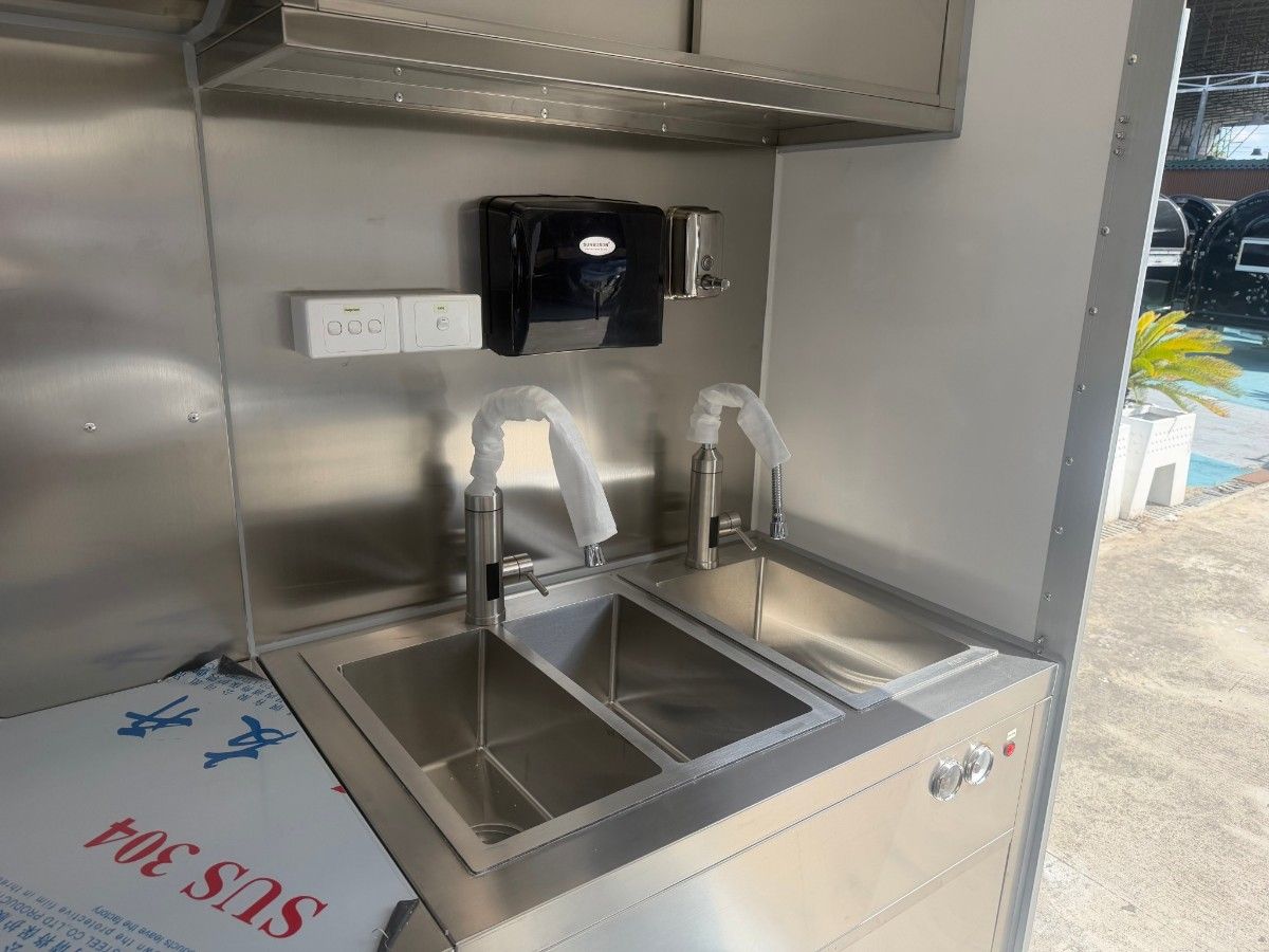 Stainless steel double sink and water faucet installed inside a Chris Machinery food trailer