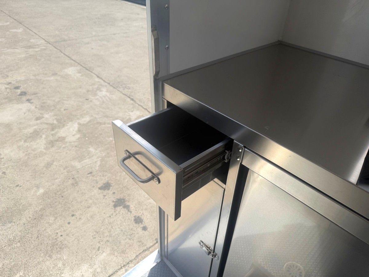 Open stainless steel drawer and workbench counter inside a Chris Machinery food trailer interior