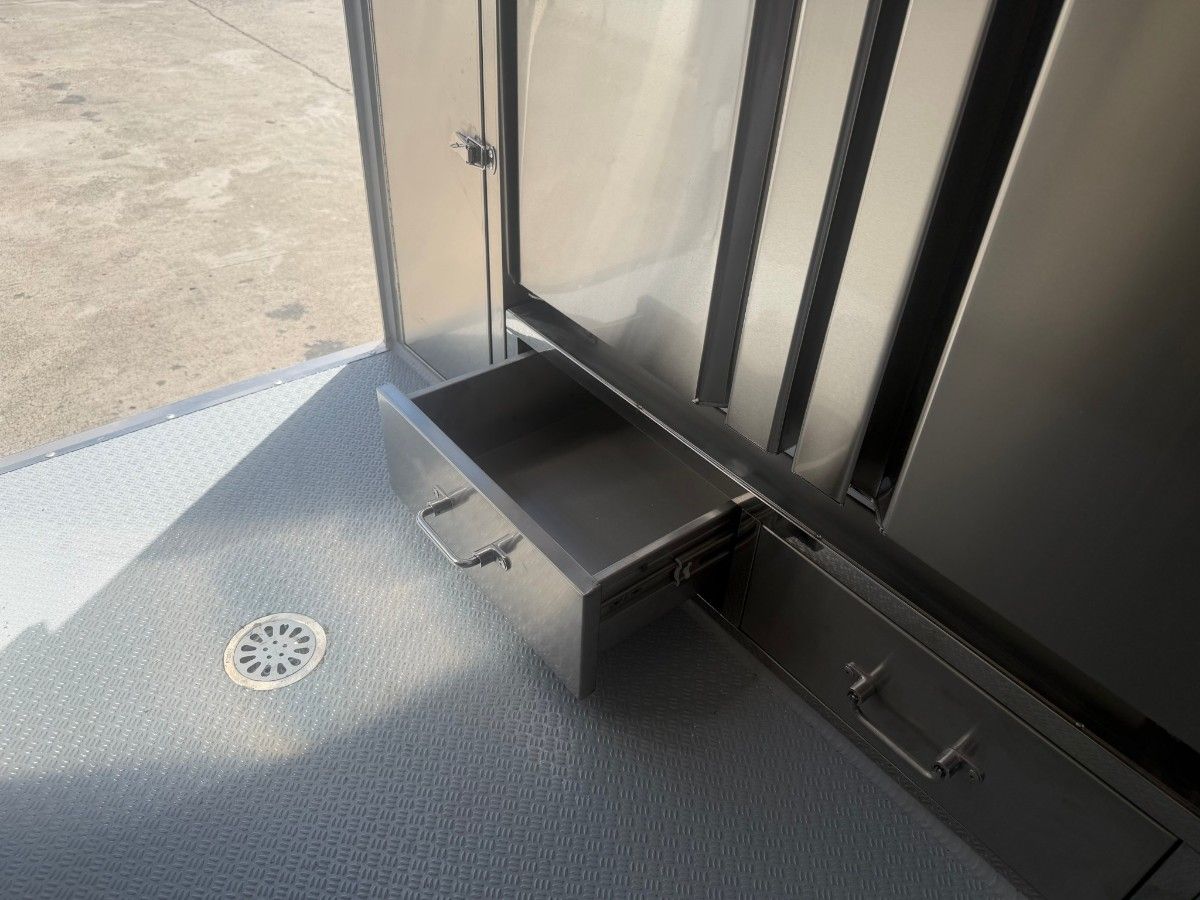 Stainless steel spice rack and utility box mounted inside a Chris Machinery food trailer