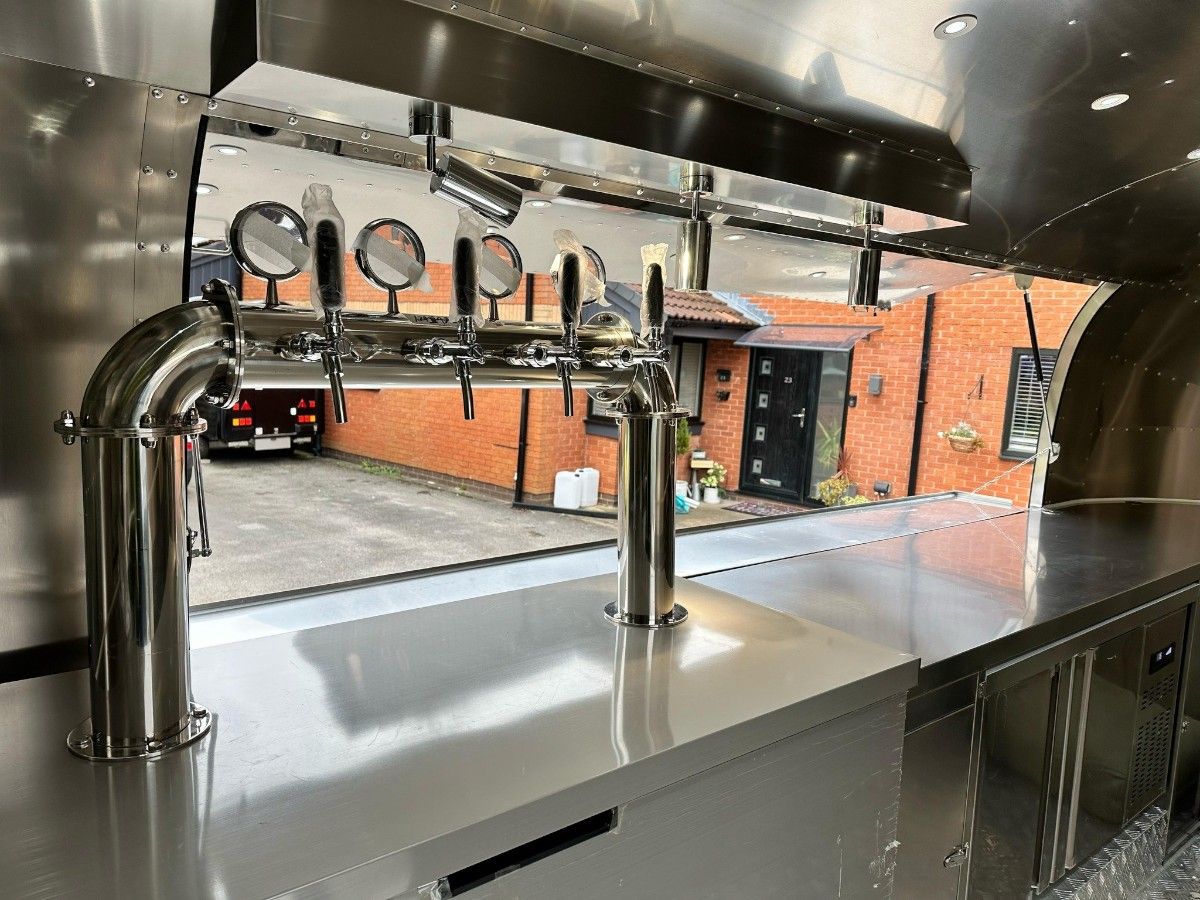 Stainless steel bar counter with beer taps inside a Chris Machinery food trailer
