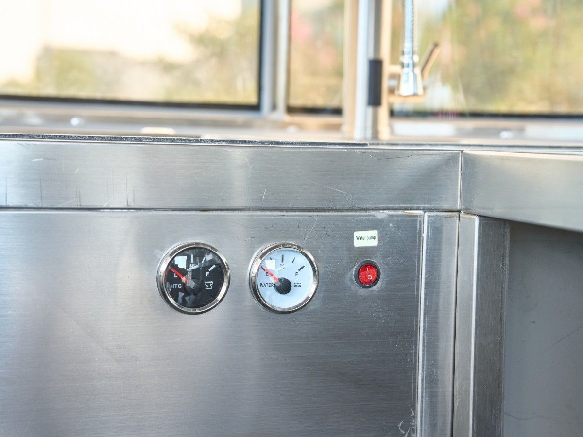 Stainless steel workbench with integrated water pressure gauges inside a Chris Machinery food trailer