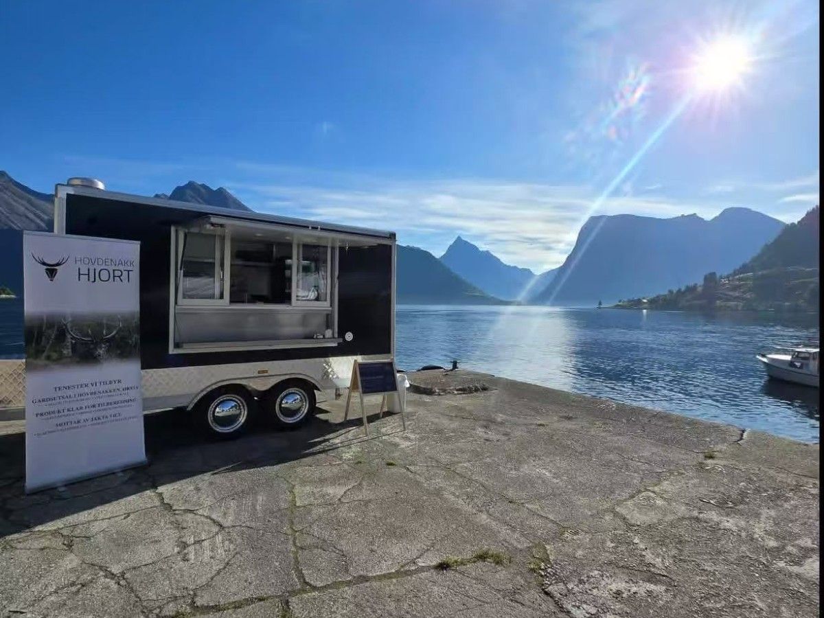 Chris Machinery food trailer parked by scenic lakeside road during outdoor event