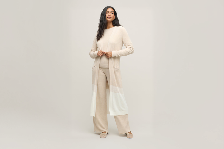 chic loungewear that feels like a continuous, warm hug all day. A woman wearing a cozy, soft knit Barefoot Dreams CozyChic UltraLite cardigan in a neutral taupe color.