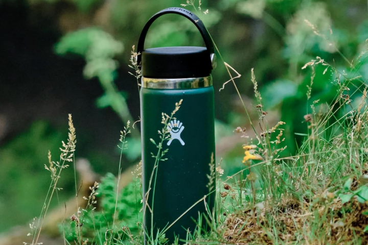A sleek, matte-finish Hydro Flask wide mouth insulated water bottle standing in a green scenery