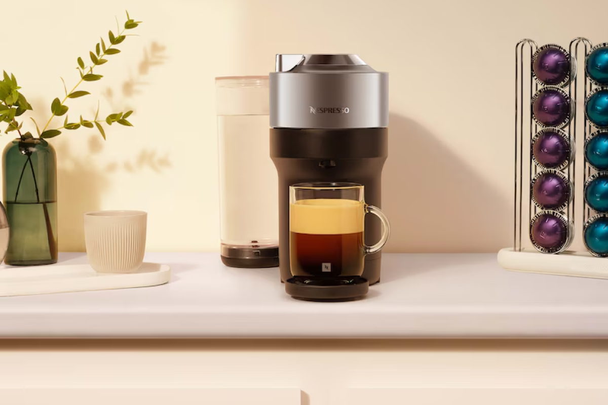 A compact Nespresso Vertuo Pop+ espresso machine brewing a fresh cup of coffee with thick, rich crema.