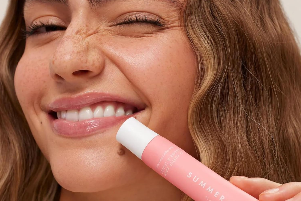 A sleek tube of Summer Fridays Tinted Lip Butter Balm sitting next to a soft, glossy swipe of the product.