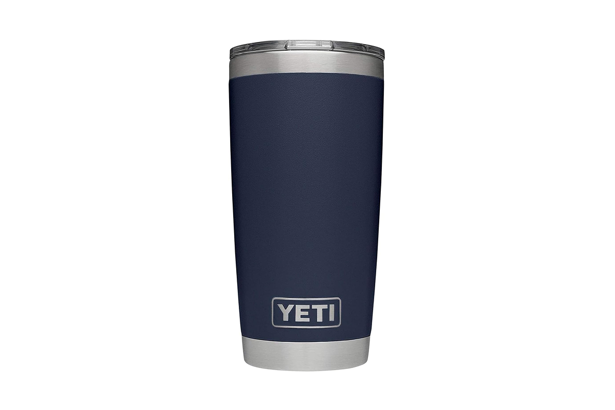 A durable, stainless steel Yeti Rambler insulated tumbler sitting on a rugged outdoor wooden table.