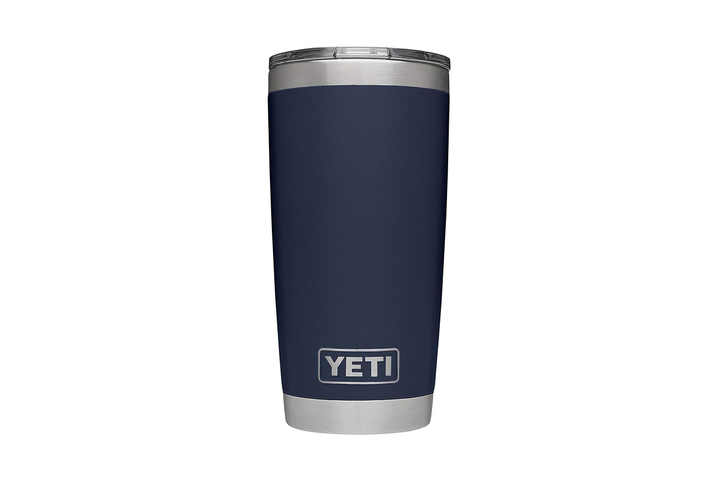A durable, stainless steel Yeti Rambler insulated tumbler sitting on a rugged outdoor wooden table.