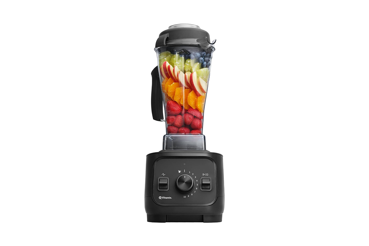 A powerful black Vitamix Explorian blender filled with a vibrant, freshly blended green wellness smoothie.