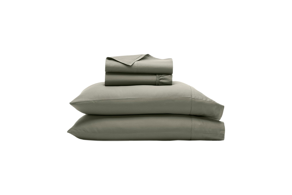 Crisp, neatly made bed with a high-end luxury sheet set and plush pillows in a bright, modern bedroom.