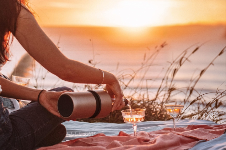 An elegant, double-walled insulated stainless steel wine and champagne chiller bucket keeping a premium bottle of bubbly cold during a romantic outdoor date.