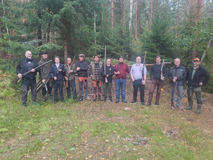Kursdeltagare med hörselskydd visar ett historiskt gevär på skjutbanan.
