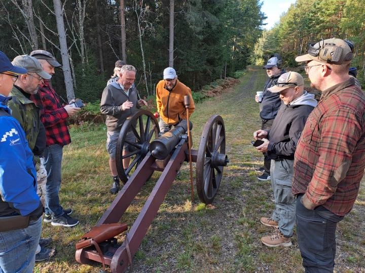 Deltagare får instruktion vid ett bord med historiska vapen och utrustning.