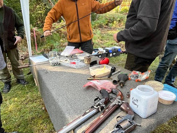 Kursledare visar handhavandet av ett historiskt gevär för en deltagare.