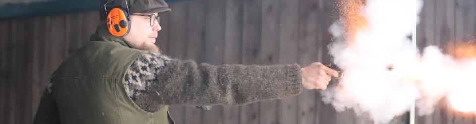 En skytt avfyrar en historisk pistol med svartkrut på en skjutbana.