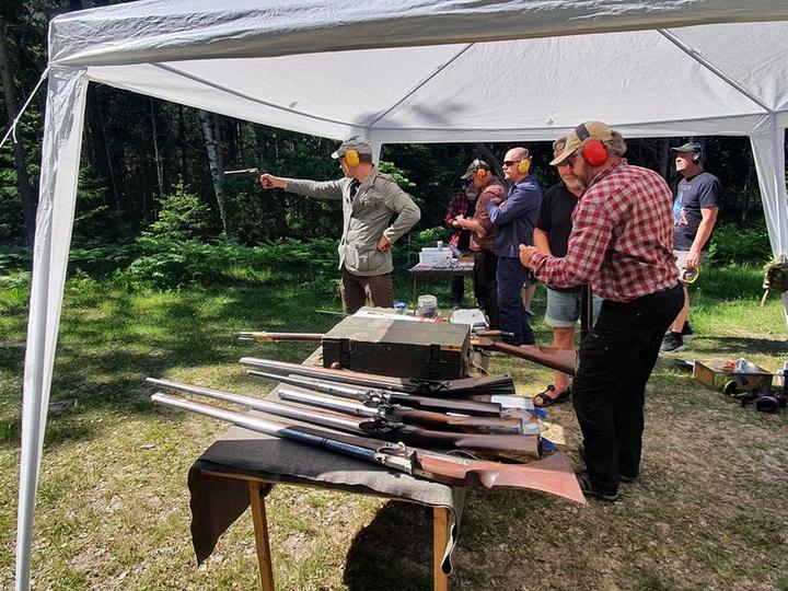 Kursdeltagare med hörselskydd på en skjutbana utomhus.