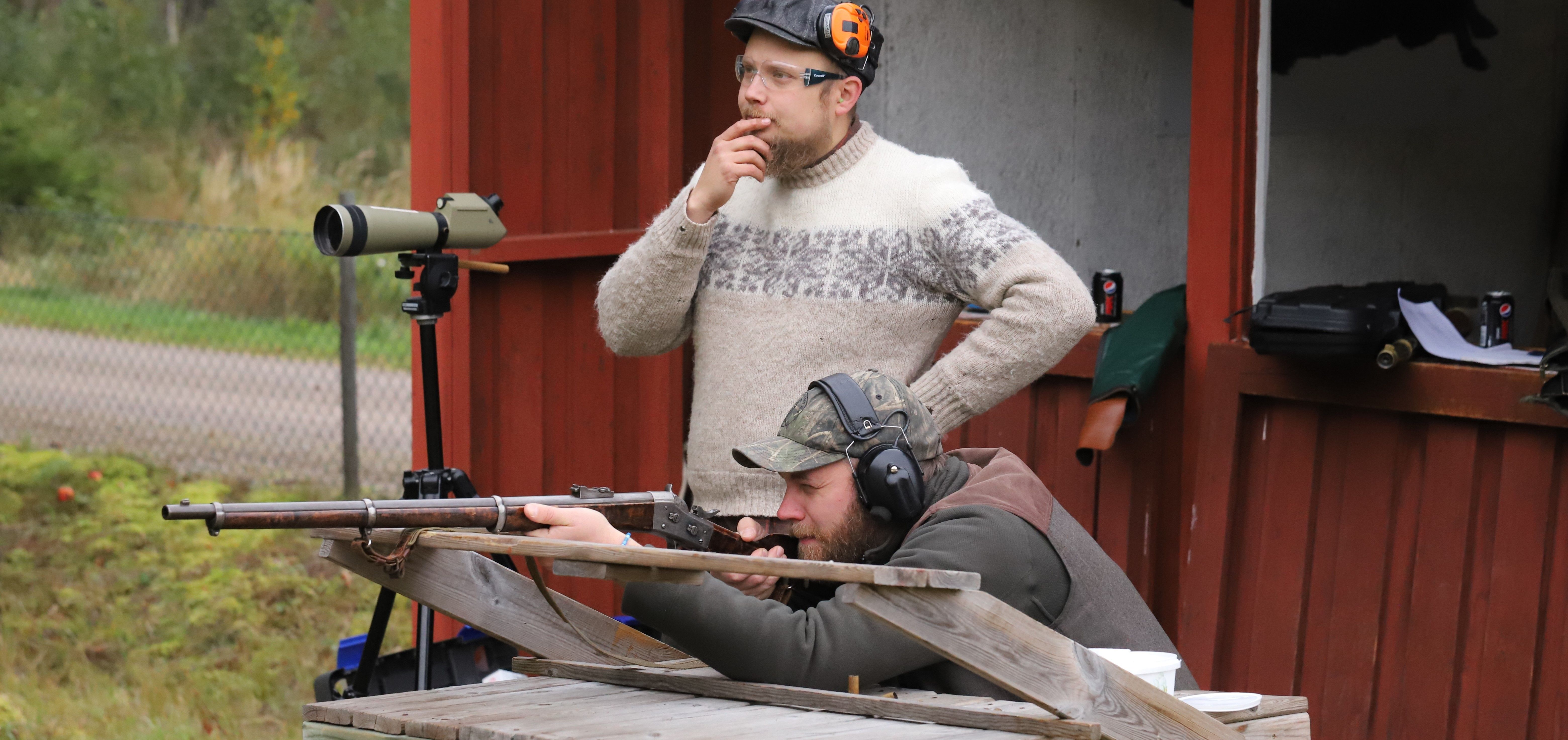 En skytt avfyrar ett historiskt gevär på en skjutbana med hörselskydd.