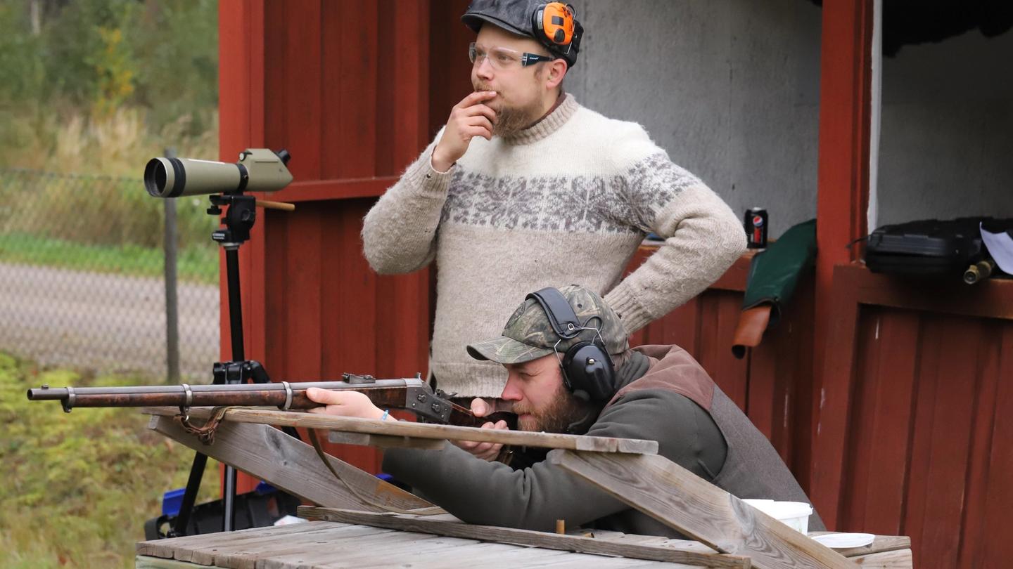 En skytt avfyrar ett historiskt gevär på en skjutbana med hörselskydd.