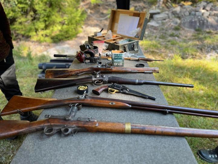 Kursdeltagare undersöker antika vapen på ett bord inomhus.