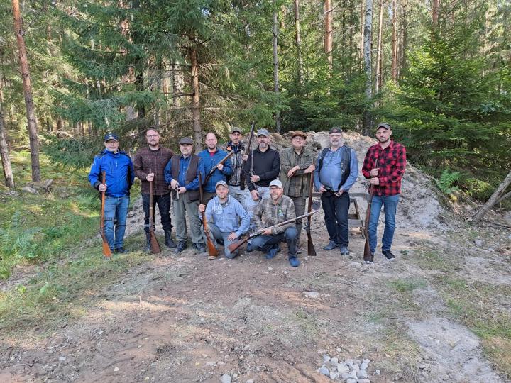 Kursdeltagare samlas kring en historisk kanon på skjutbanan.