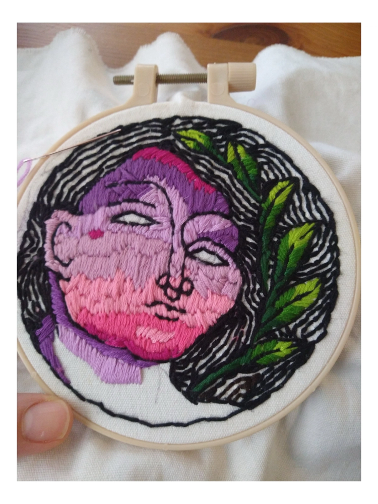 A stylized face with leaves and surrounded by hair.