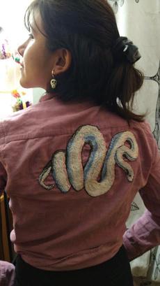 Jess posing with a shirt with a white snake embroidered in the back.