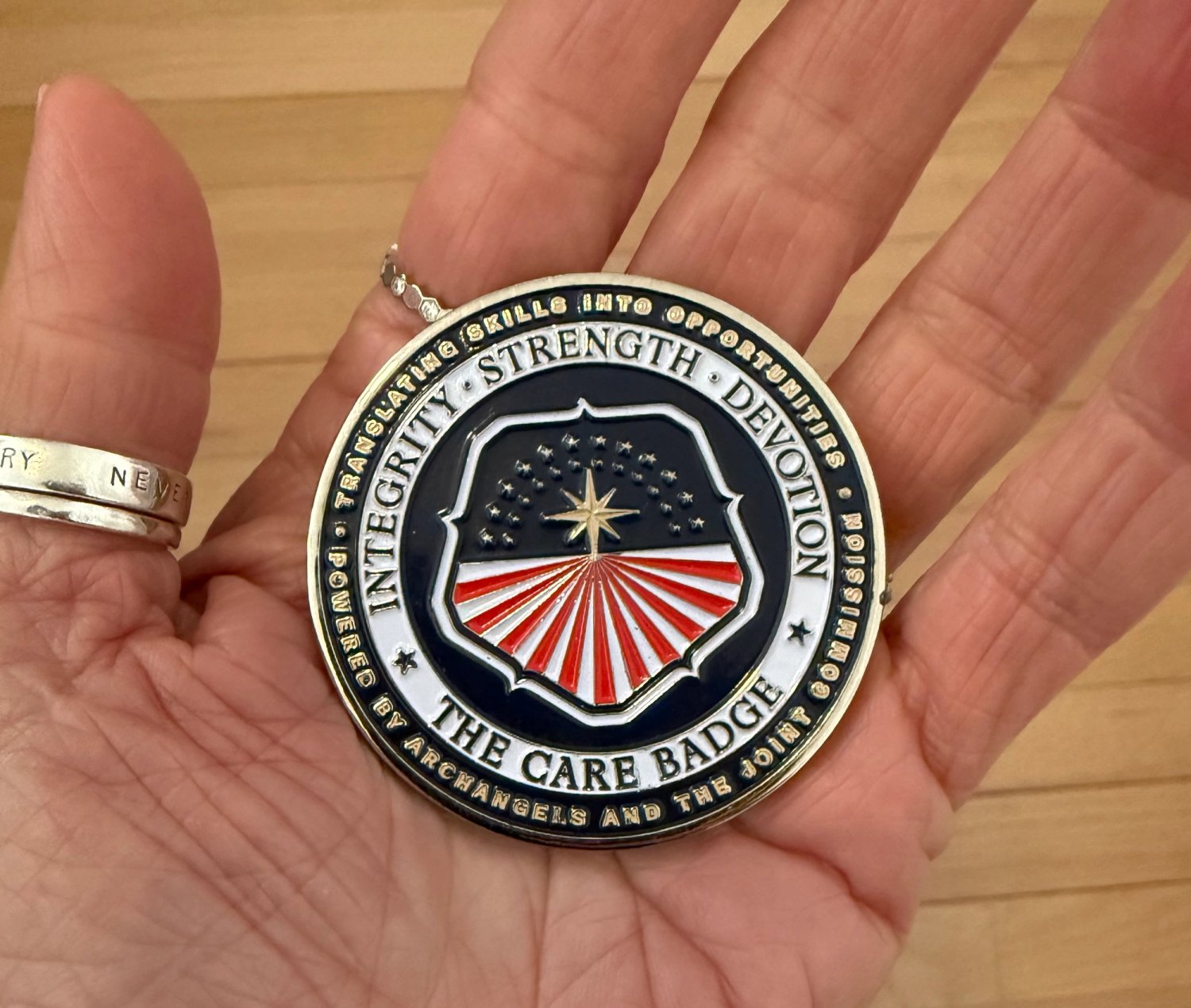 The Care Badge challenge coin in the palm of a woman's left hand