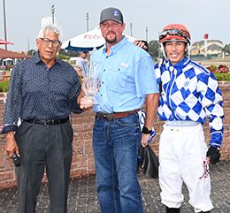The connections of Cash Back Hero accept the $51,000 Covered Bridges Stakes (G3)  winning trophy at Prairie Meadows on Sunday.