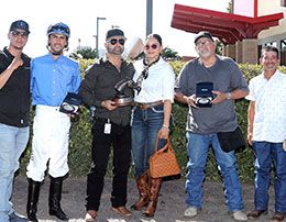 The winning connections of Handin Out Candy accept the -Racing Video New Mexico Distance Challenge stakes trophy at The Downs.