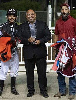 Los Alamitos Director of Marketing Orlando Gutierrez presents the Mildred Vessels Memorial Handicap stakes trophy to jockey Martin Arriaga and trainer Albert Valles.