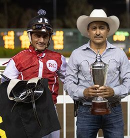 Ramiro Castillo and Jacob Enriquez accept the Go Man Go Stakes trophy at Los Alamitos Sunday night.