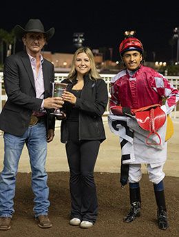 Jennifer Jaramillo presents the Dashingly Handicap stakes trophy to trainer James Glenn, Jr., and jockey Henry Lopez.