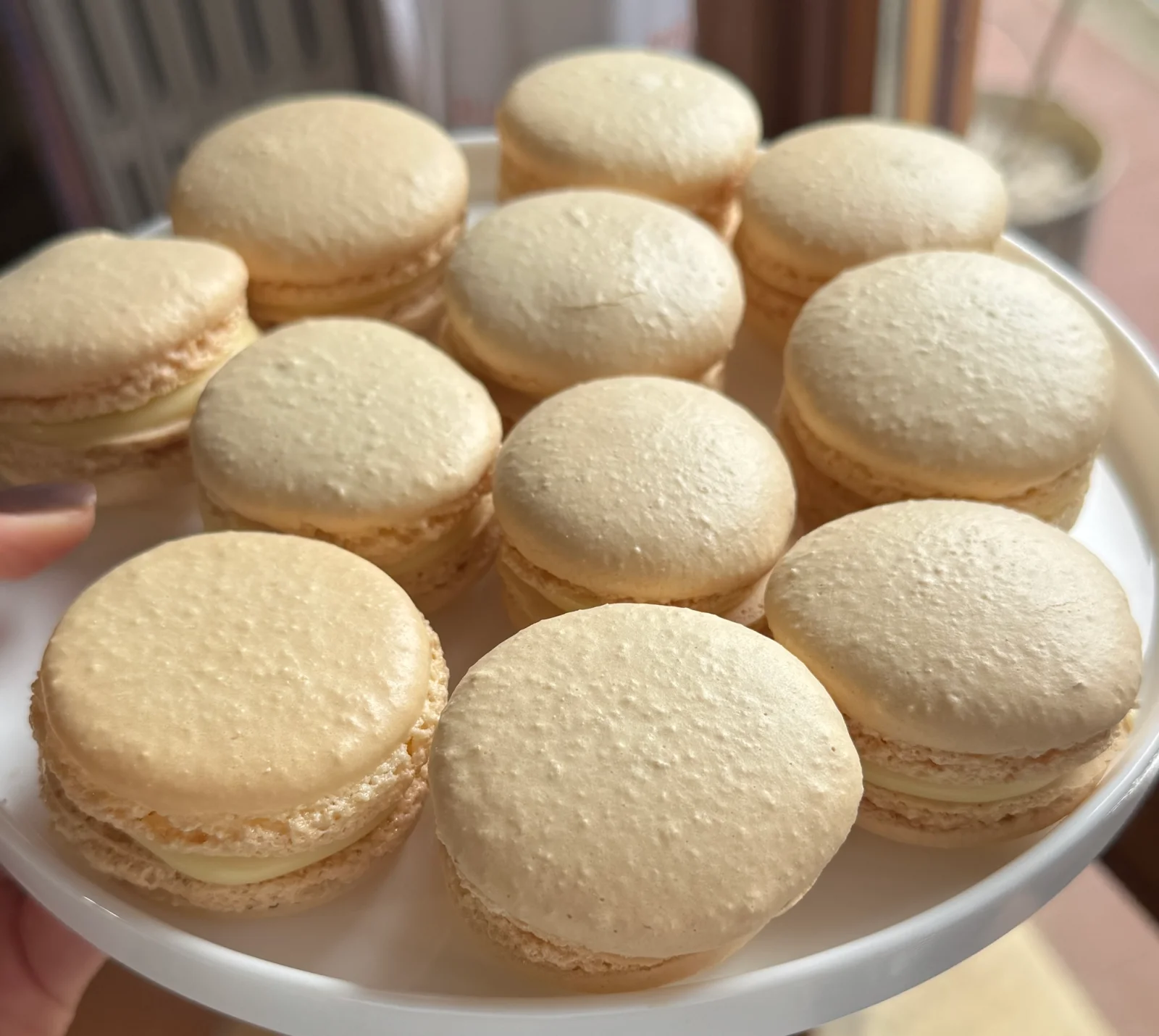 Vassoio con macarons al cioccolato bianco e caramello salato su un tavolo in legno con motivo a spina di pesce.